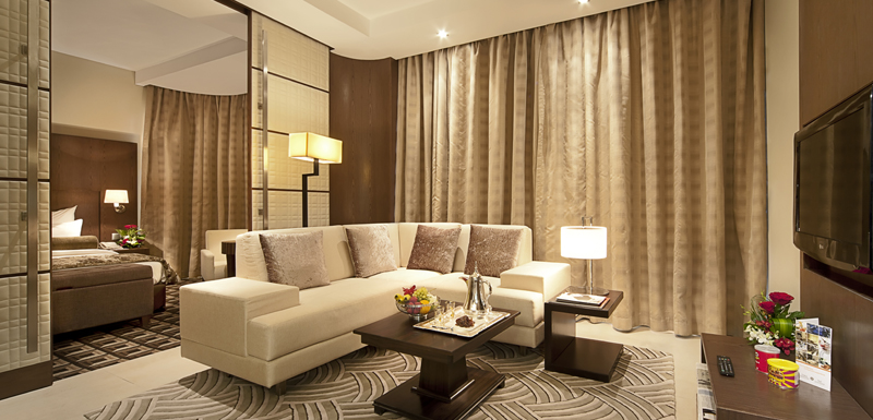 big living room with satellite TV, air conditioning and comfortable modern furniture including couches and tables and large windows with panoramic views of Abu Dhabi city in the United Arab Emirates